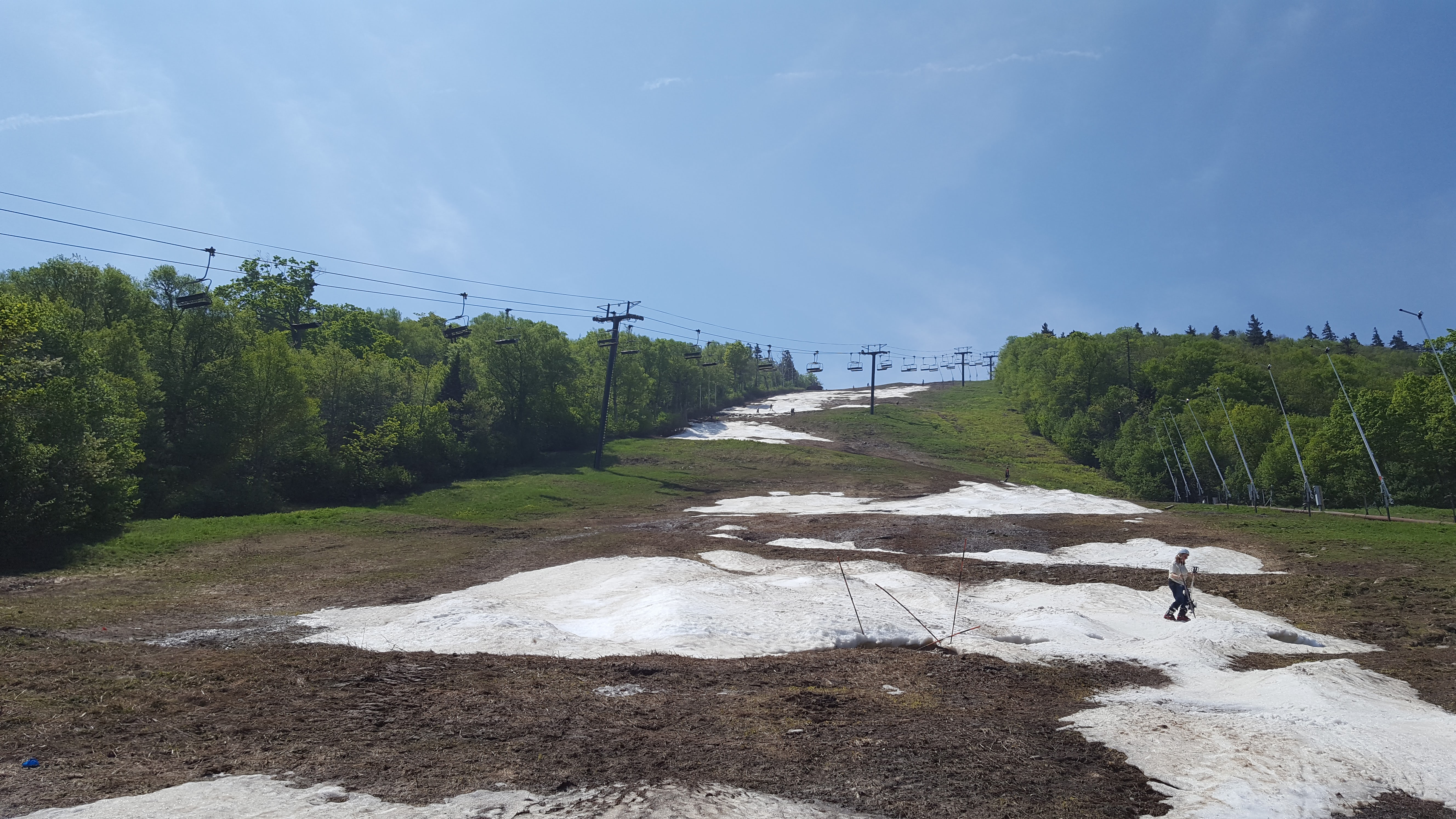 the superstar trail at the end of the ski season, patches of snow on grassy trail, ski lift poles